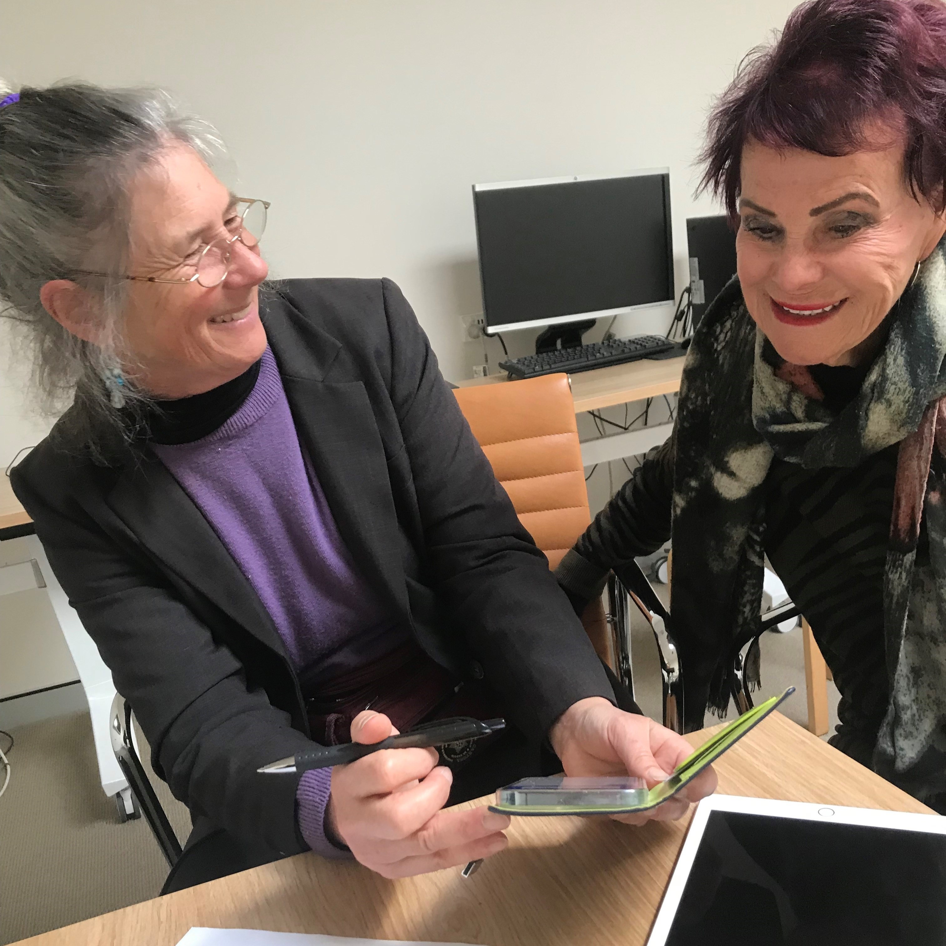 Two women laughing over a phone